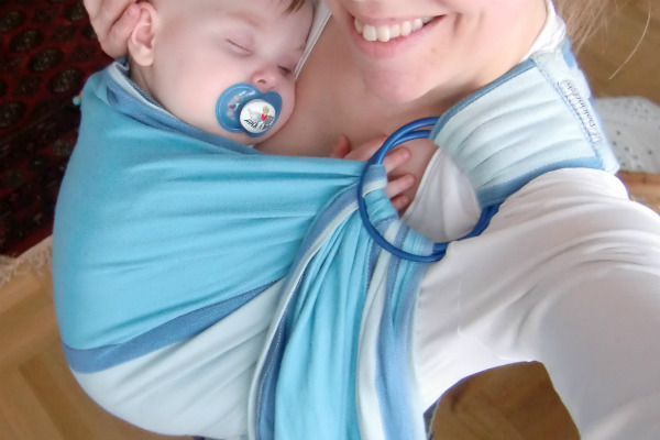 Bära en nyfödd bebis i bärsjal. Bebis sover i ringsjal.