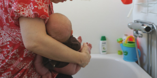 När bebisen amningsvägrar. Bebis får hjälp av sin mamma att kissa i badkaret.