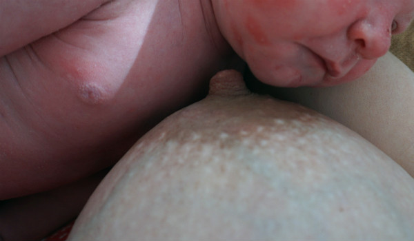 När det gör ont att amma. Bebis vid bröst efter avslutad amning.