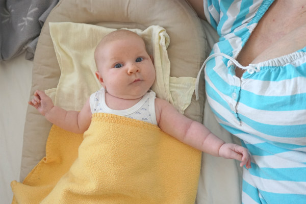 Socialstyrelsens sovråd för bebisar. Bebis i babynest tittar mot kameran.