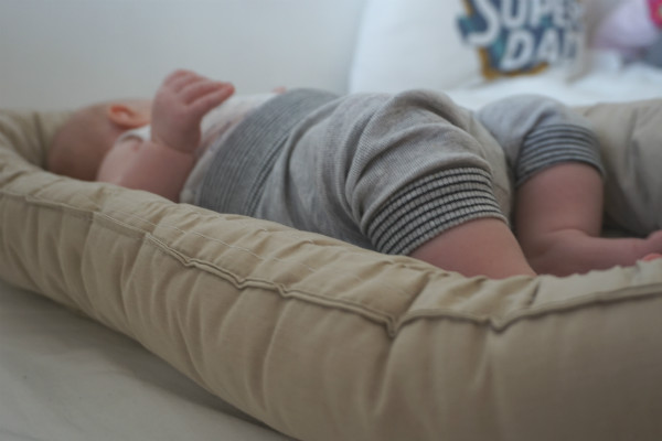 Socialstyrelsens sovråd för bebisar. Baby ligger i babynest, vars kant syns i förgrunden.