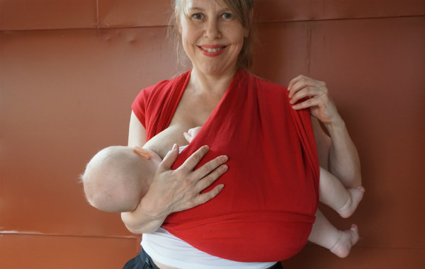 Bildserie: Amma i trikåsjal. Bebis ligger ned och ammar i röd bärsjal. Mamman justerar tyget vid sin ena axel.