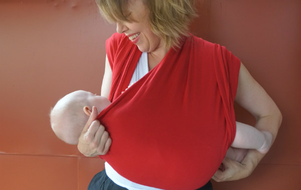 Bildserie: Amma i trikåsjal. Bebis ligger ned i röd bärsjal, mamman drar åt tyg om nacken.