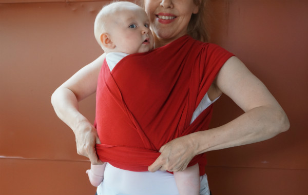 Bildserie: Amma i trikåsjal. Bebis sitter upp i röd bärsjal.