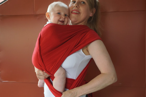 Bildserie: Amma i trikåsjal. Bebis sitter upp i röd bärsjal.