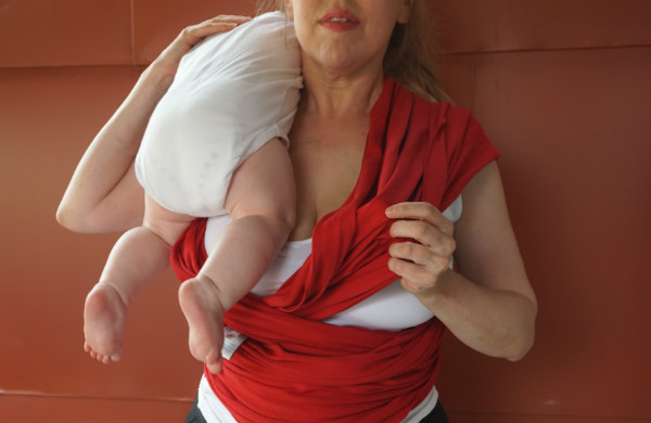 Bildserie: Amma i trikåsjal. Bebis ligger mot axeln på sin mamma, som har en röd bärsjal.