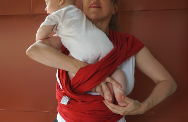 Bildserie: Amma i trikåsjal. Bebis stoppas in i röd bärsjal.