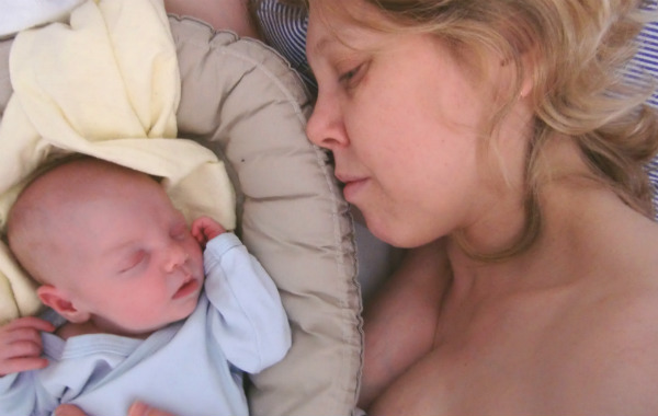 Tips till blivande förälder. Bebis sover i babynest, mamma bredvid.