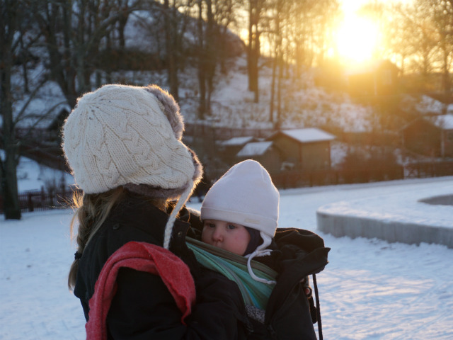 Tips om hur du ammar i bärsele och bärsjal. Bebis ammar i bärsjal utomhus, vinter och snö och lågt liggande sol i park.