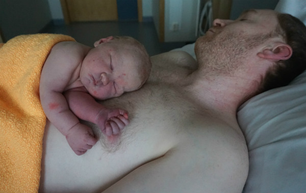 Amningsvänlig tilläggsmatning. Nyfödd sover på BB på pappans nakna bröst.