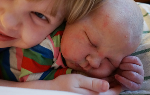 Amningsdagbok del tre. Nyfödd bebis får kram av äldre syskon.