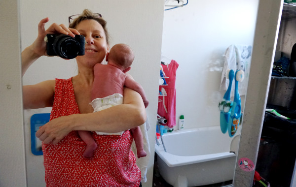 Amningsdagbok del två. Mamma håller i nyfödd bebis, tar en selfie i badrummet.
