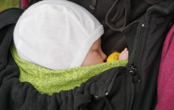 Amningsdagbok del fyra. Bebis sover utomhus i bärsjal, under en bärjacka.