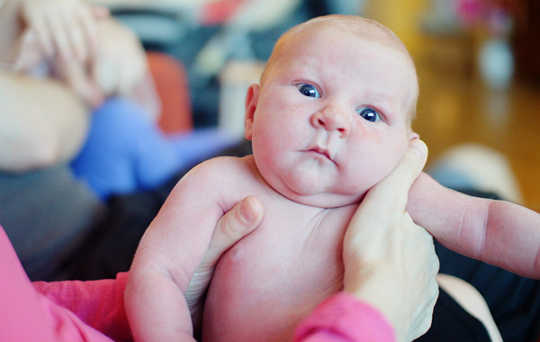 Amningsdagbok del tre. Nyfödd bebis som hålls av en vuxen tittar med stora ögon mot kameran.