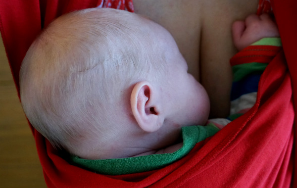 Amningsdagbok del tre. Nyfödd bebis sover i röd bärsjal.