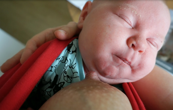 Tips om hur du ammar i bärsele och bärsjal. Bebis somnar efter amning i röd bärsjal, inomhus.