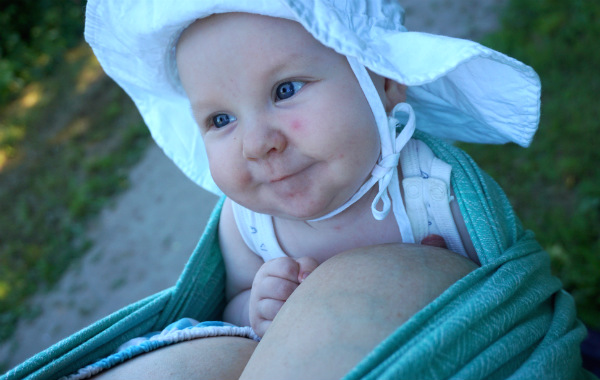 Tips om hur du ammar i bärsele och bärsjal. Glad bebis har precis ammat i bärsjal utomhus, sommar.