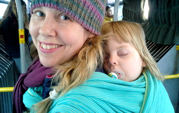 Bära barn på ryggen, barn har somnat i bärsjal på mammas rygg, på buss.