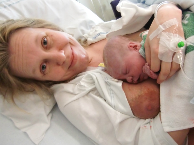 Kvinna med alldeles nyfödd bebis på bröstet, på sjukhus.