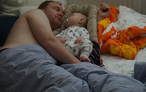 Amningsdagbok del fyra. Pappa sover bredvid bebis i babynest.