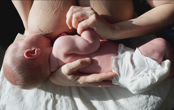 När bebisen vill amma jämt. Bebis ammar, mammans håller i bebisens hand.