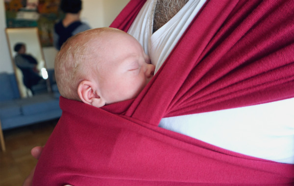 Amingsprylar. Bebis i bärsjal på sin pappas bröst.