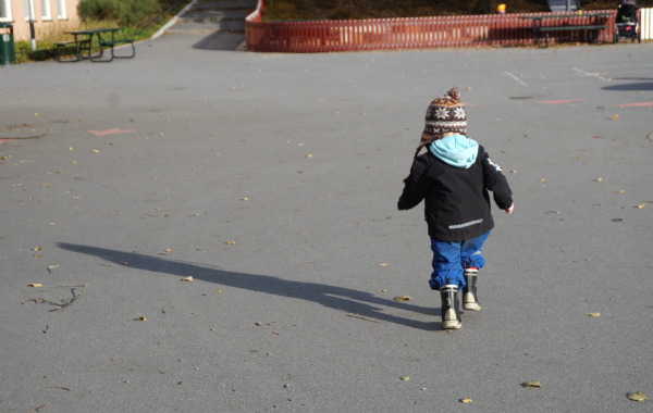 Barn springer i lekpark utomhus, höst.