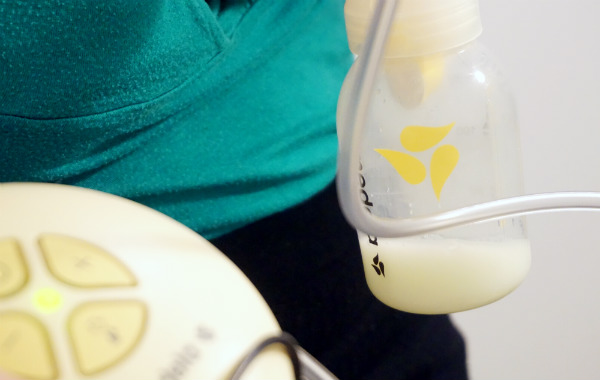 Pumpa bröstmjölk, närbild på pump, inklusive flaska med bröstmjölk i.