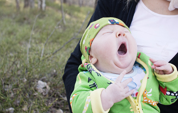 Kan amning ta för mycket energi? Liten bebis gäspar utomhus.