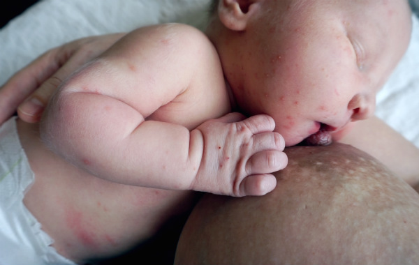 Amningsvänlig tilläggsmatning. Nyfödd sover vid bröstet.