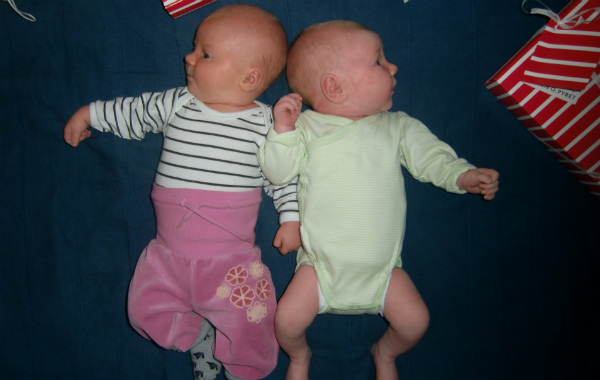 Amningsvänlig tilläggsmatning. Två nyfödda bebisar bredvid varandra på en filt.