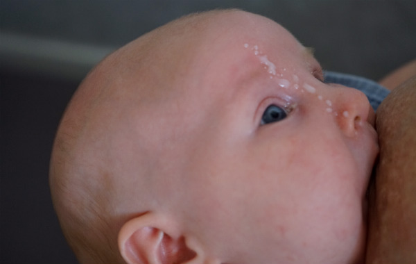 Amningsbildextra. Bebis ammar och har mjölkdroppar i ansiktet.