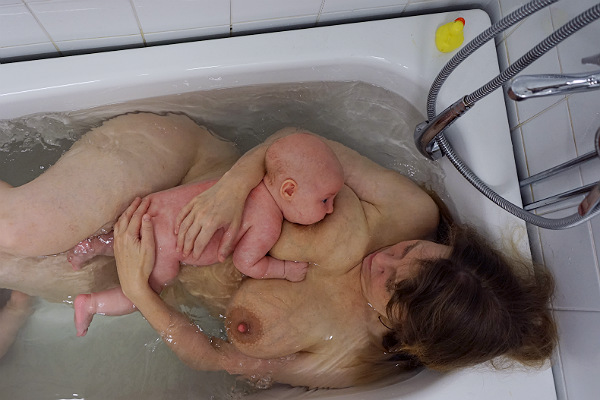 Amma i badkaret. Tillbakalutad amning i badkar, mamma och bebis.