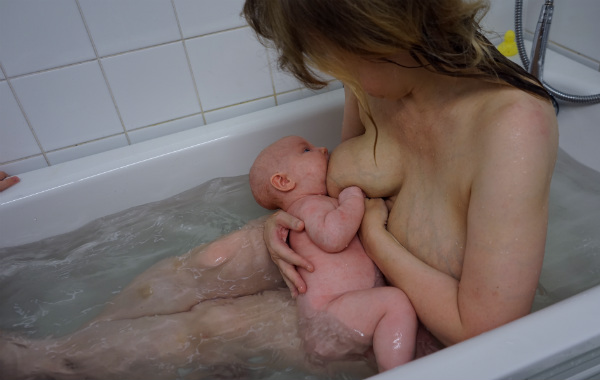Amma i badkaret. Bebis ammar liggande i badkaret.