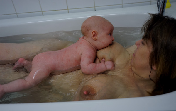Amma i badkaret. Bebis ammas i vattnet i badkaret, mage mot mage med mamman.