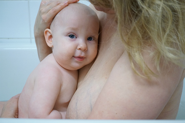 Matintroduktion. Bebis vilar mot mammas bröst i badkaret.