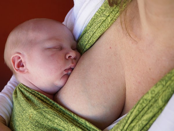 Att sluta amma bebis kan göras smidigast med mycket hudkontakt, här syns sovande bebis i grön bärsjal.